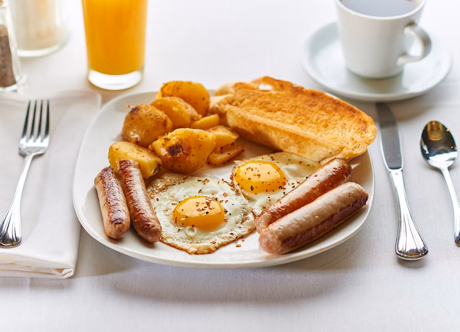 A hearty full English breakfast with eggs, sausages, potatoes, and toast.